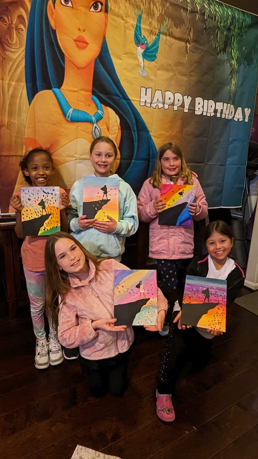 Kids holding finished canvas paintings at a SIS birthday party